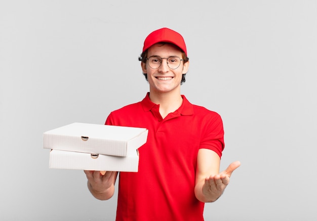 Pizzalieferjunge, der glücklich mit freundlichem, selbstbewusstem, positivem Blick lächelt und ein Objekt oder Konzept anbietet und zeigt