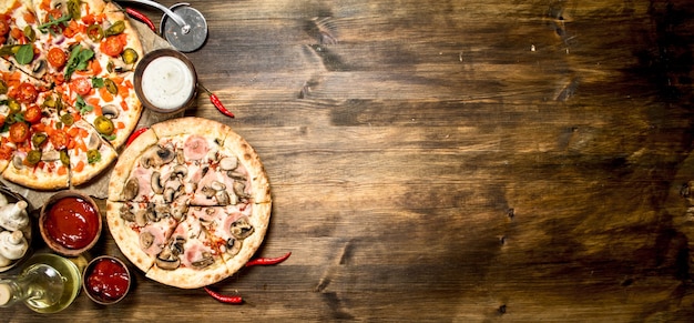 Pizzas frescas con chorizo y verduras. Sobre una mesa de madera.