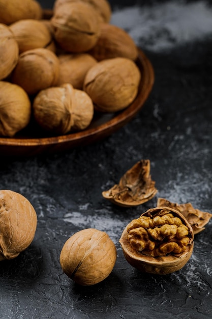 Placa con algunas nueces crudas y cáscara sobre fondo oscuro