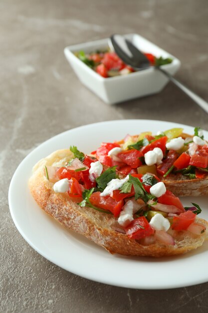 Placa con aperitivos bruschetta en mesa con textura gris