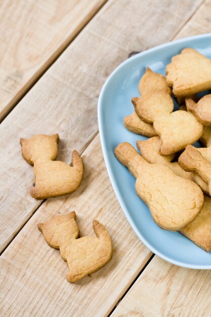 Placa azul com deliciosos biscoitos em forma de figuras de gatos e guitarras na mesa de madeira sem pintura