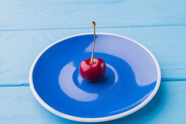 Placa azul com uma cereja em fundo de madeira