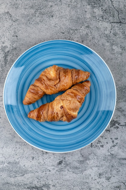 Placa azul de croissants de chocolate fresco sobre la superficie de piedra.