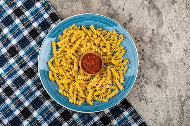 Foto placa azul de massa fusilli crua na mesa de pedra.