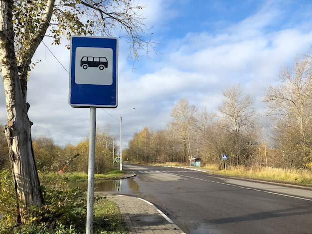 Placa azul de parada de ônibus ao lado da estrada