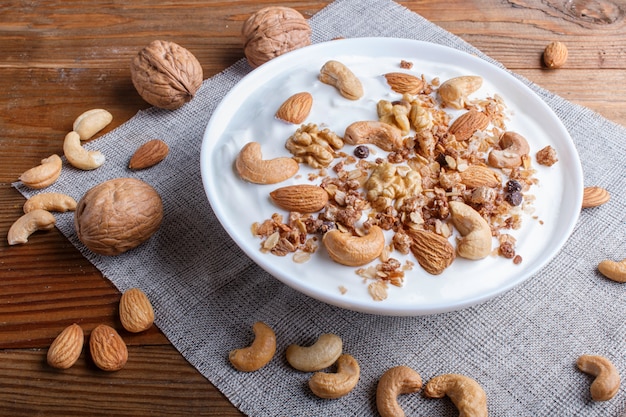 Placa branca com iogurte grego, granola, amêndoa, castanha de caju, nozes