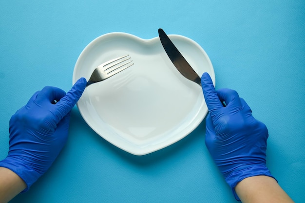 Foto placa branca em forma de coração sobre fundo azul garfo e faca