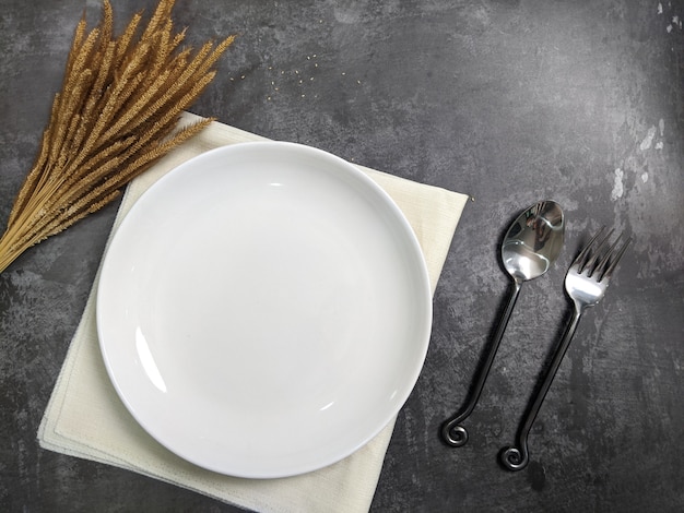 Placa de cerámica blanca vacía con tenedor y cuchara sobre fondo de mesa de hormigón de piedra gris. Copia espacio Concepto de receta de menú