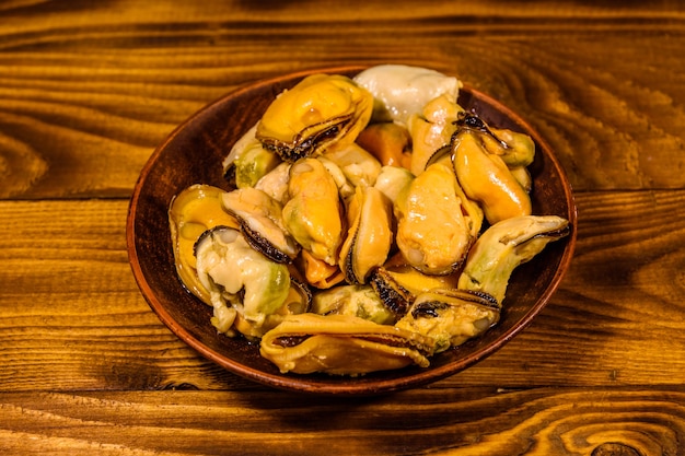 Foto placa de cerámica con mejillones preparados sobre mesa de madera rústica