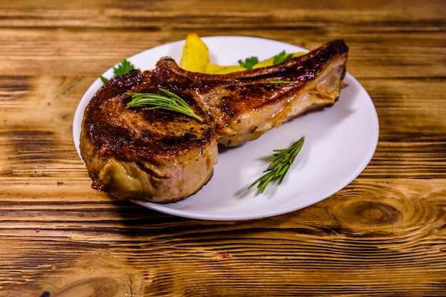 Placa con chuletón asado y patatas sobre mesa de madera rústica