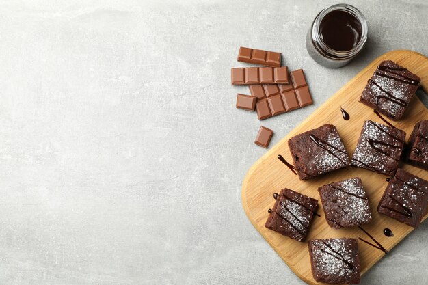 Placa com fatias de bolo de chocolate e chocolate no fundo cinza, espaço para texto