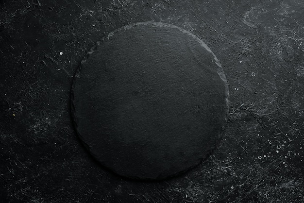 Placa de ardósia redonda de pedra preta em um fundo de pedra preta Vista superior Espaço livre para o seu texto