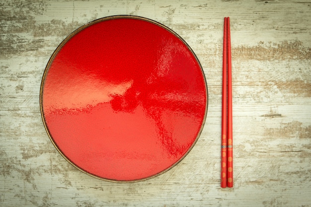 Foto placa de cerâmica oriental e pauzinhos em vermelho