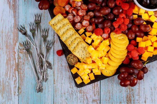 Placa de charcutaria com cubo de queijo, presunto, uvas, biscoitos e damascos