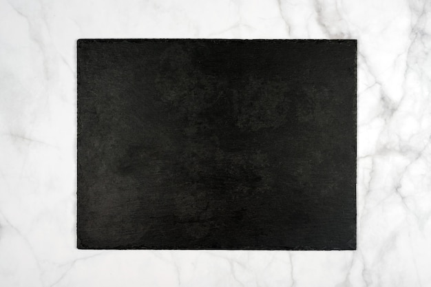 Placa de corte retangular de ardósia preta, tabuleta vazia no mármore claro.