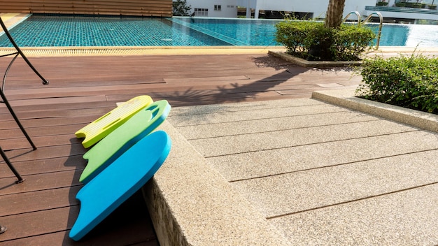 Placa de espuma de natação verde e azul amarela colocada na borda da passarela íngreme de natação perto de almofadas flutuantes de espuma de piscina para crianças