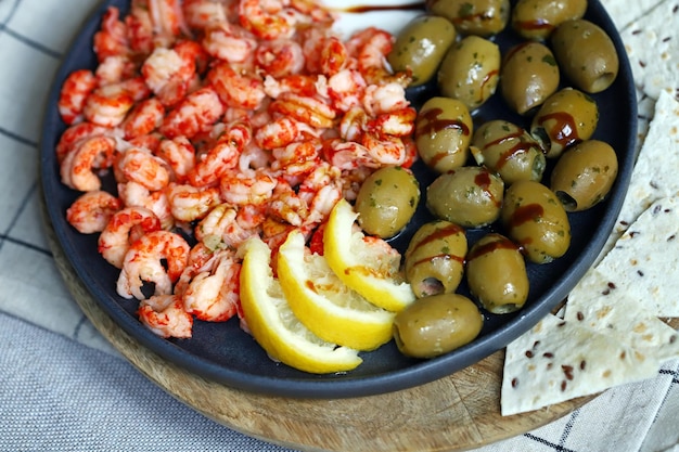 Placa de foco suave com camarões cozidos com azeitonas limão e molho Lanche saudável comida italiana