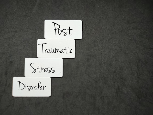 Placa de madeira branca com as letras PTSD e as palavras transtorno de estresse pós-traumático