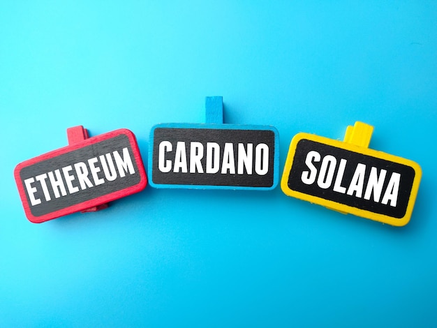 Placa de madeira colorida escrita com o texto ETHEREUM, CARDANO, SOLANA em um fundo azul. Conceito de negócios.