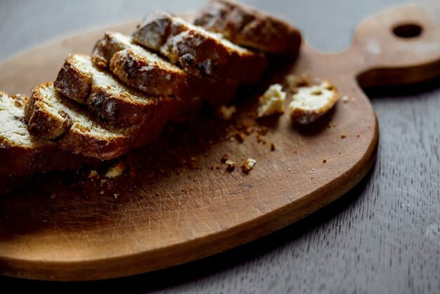 Placa de madeira com sobremesa de pão servido e corte em fatias.