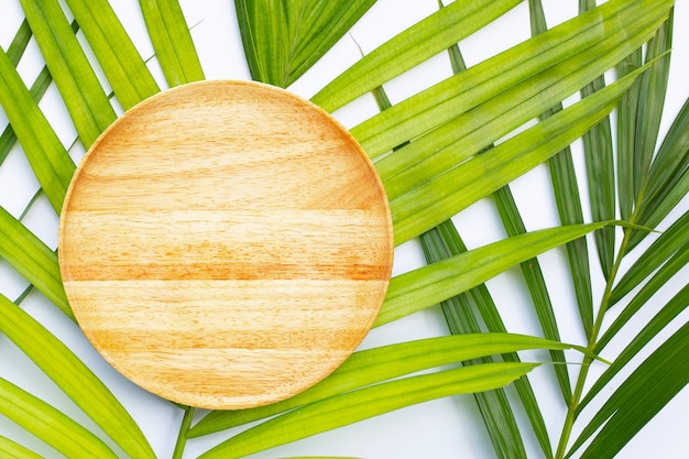 Placa de madeira vazia em folhas de palmeira tropical em fundo branco. Vista do topo