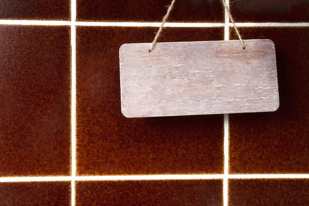 Placa de madeira, vazio, espaço para texto perto da parede de azulejos marrom