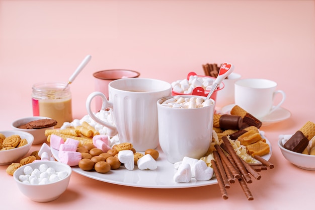 Placa de marshmallows, chocolates e biscoitos de chocolate quente na mesa-de-rosa