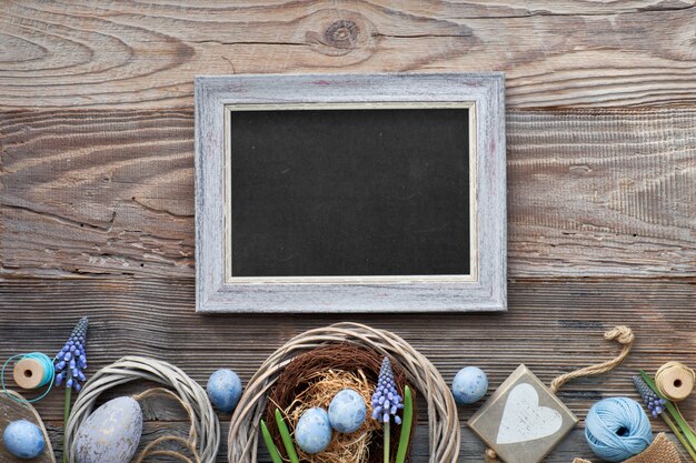 Placa de páscoa preto com ovos de páscoa, flores e decorações de primavera em madeira rústica, texto