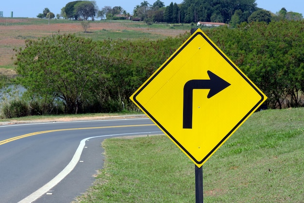 Foto placa de sinalização da curva acentuada à direita na estrada
