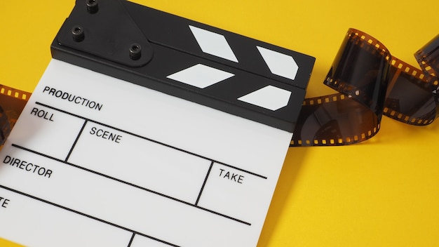 Foto placa de válvula branca pequena e rolo de filme sobre fundo amarelo. é usado na produção de filmes e vídeos.