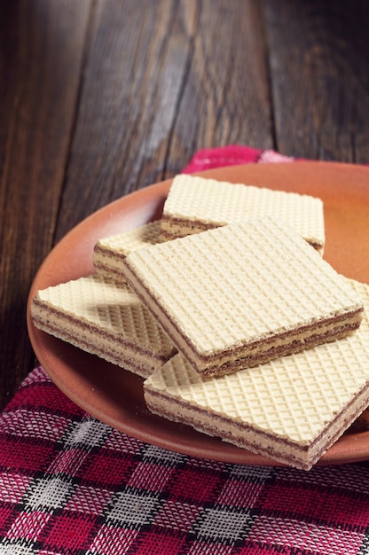 Placa con deliciosas obleas en una mesa de madera oscura.