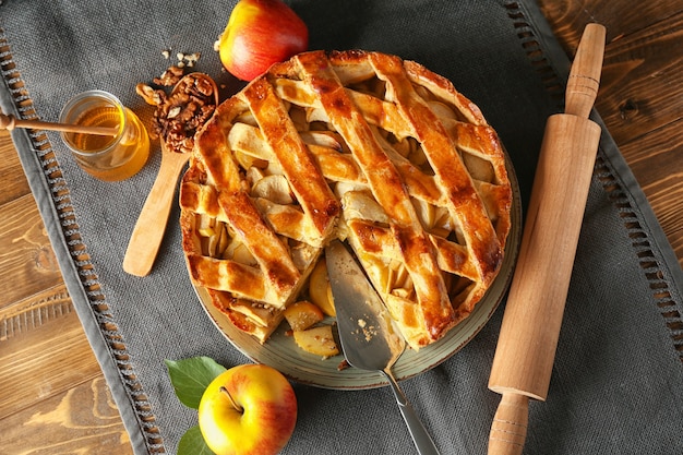 Placa con delicioso pastel de manzana en mesa de madera