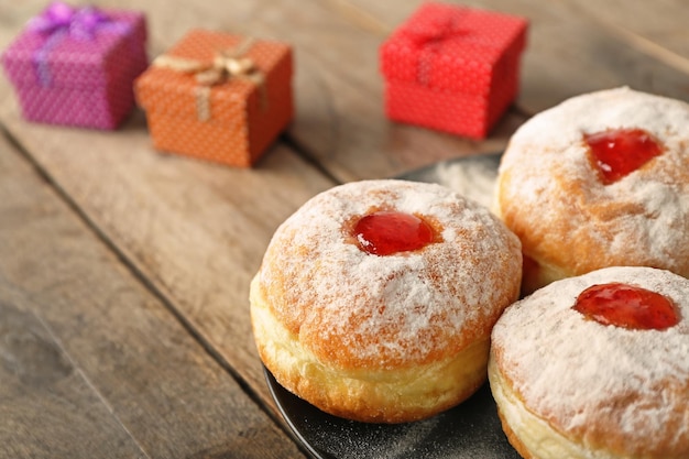 Placa con deliciosos donuts sobre fondo de madera cerca del concepto de celebración de Hanukkah