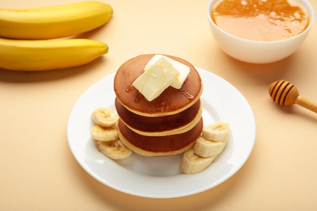 Placa con deliciosos panqueques de plátano sobre fondo beige