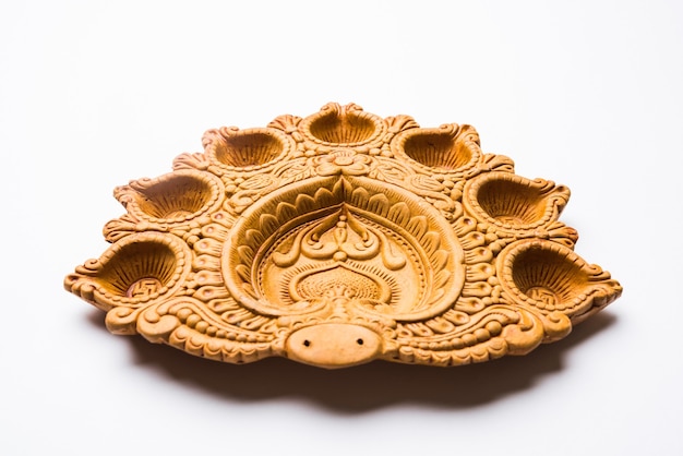 Placa Diwali Diya de diseñador bellamente tallada hecha de terracota, enfoque selectivo y aislado