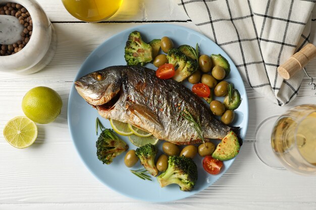 Foto placa con dorado al horno y verduras sobre fondo de madera, vista superior