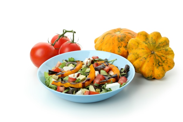 Placa con ensalada de calabaza e ingredientes aislados sobre fondo blanco.