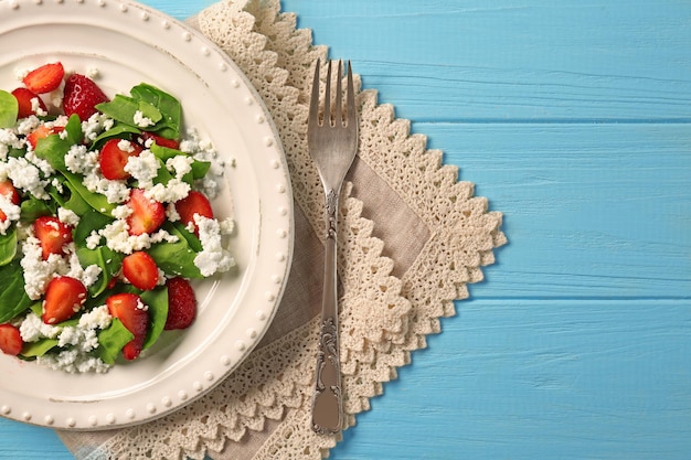 Placa con ensalada de espinacas y fresas en mesa de madera