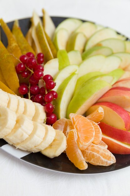 Placa con ensalada de frutas de frutas y bayas picadas en una placa negra