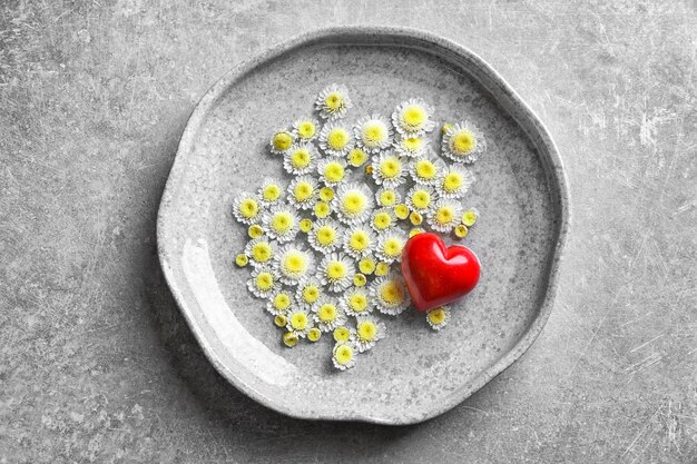 Placa con flores de agua y corazón rojo sobre fondo gris