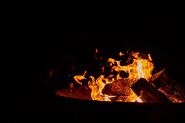 Placa de fuego con pila de maderaCeniza brillante y madera quemada en un cuenco de fuego de hierrogran hoguera en un viejo cuenco de fuego oxidado utilizado para decorar un espacio de copia de fiesta