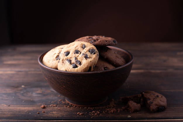 Placa con galletas de chispas de chocolate, migas sobre la mesa de madera oscura, de cerca.