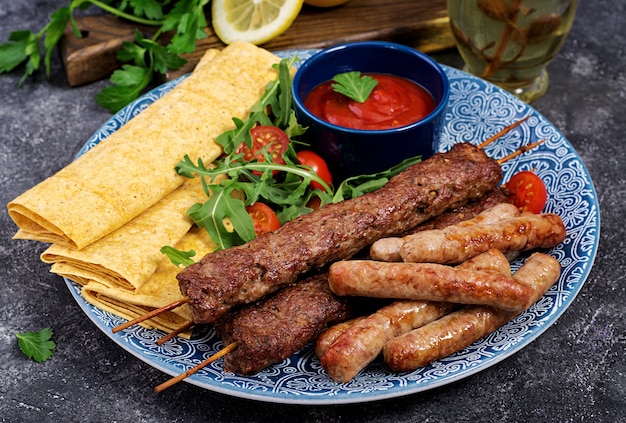 Placa de kebab de mezcla de Ramadán tradicional turco y árabe. Kebab adana, cordero y ternera sobre pan lavash con salsa de tomate.