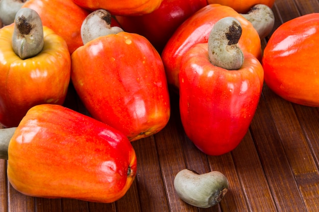 placa de madera con unos anacardos sobre una superficie de madera. Fruta fresca.