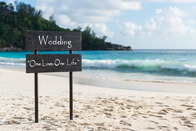 Placa de madera negra con cartel de boda en la playa