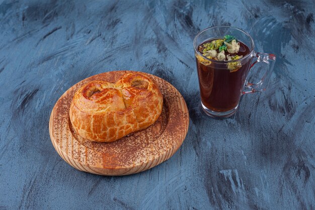 Placa de madera de pastelería fragante fresca y taza de té en la superficie de mármol.