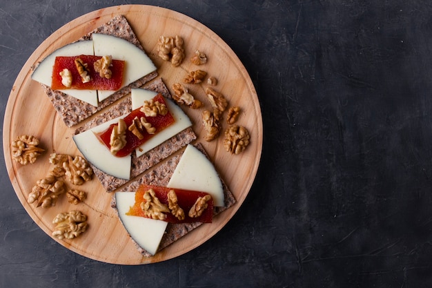 Placa de madera con queso, nueces y membrillo encima de pan tostado Comida sana