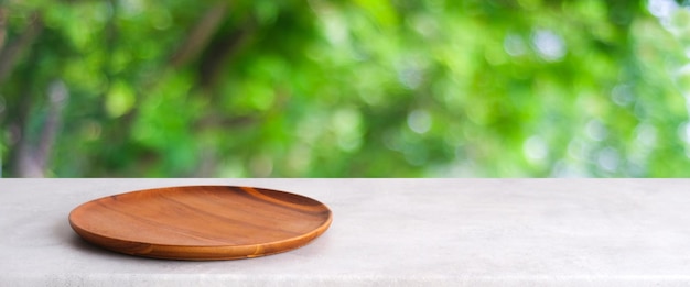 Placa de madera vacía en la mesa blanca sobre la naturaleza de los árboles verdes borrosos con fondo bokeh