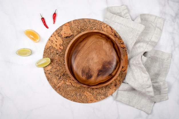 Placa de madera vacía sobre una servilleta y corcho trivet calentar con limón y pimienta.