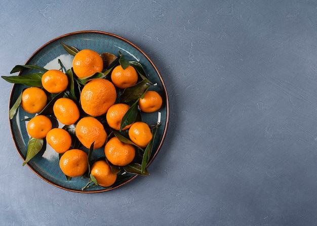 Placa con mandarinas maduras con copia espacio en un fondo gris